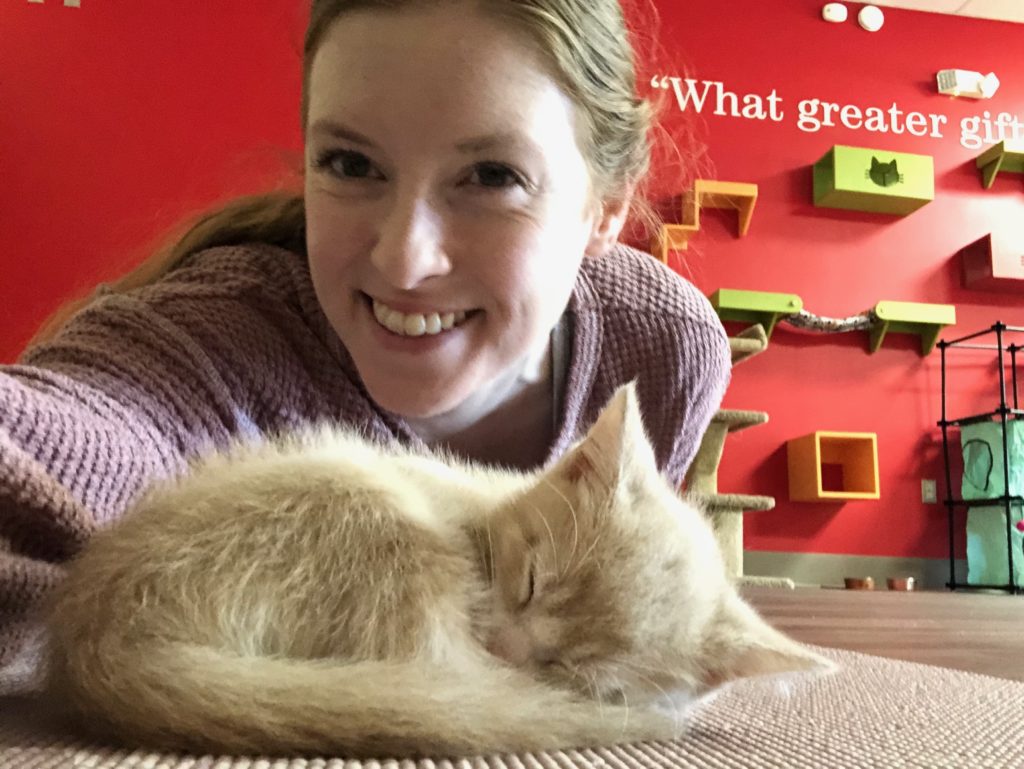 Rachel taking a selfie with a kitten sleeping on her mat